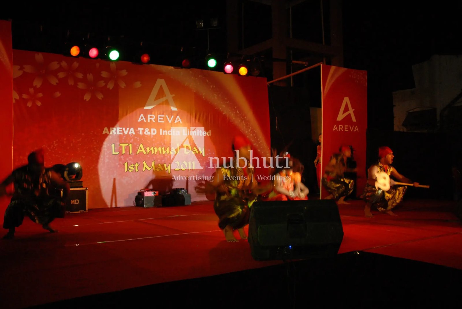 Man and woman speaking on stage at night with blue lighting